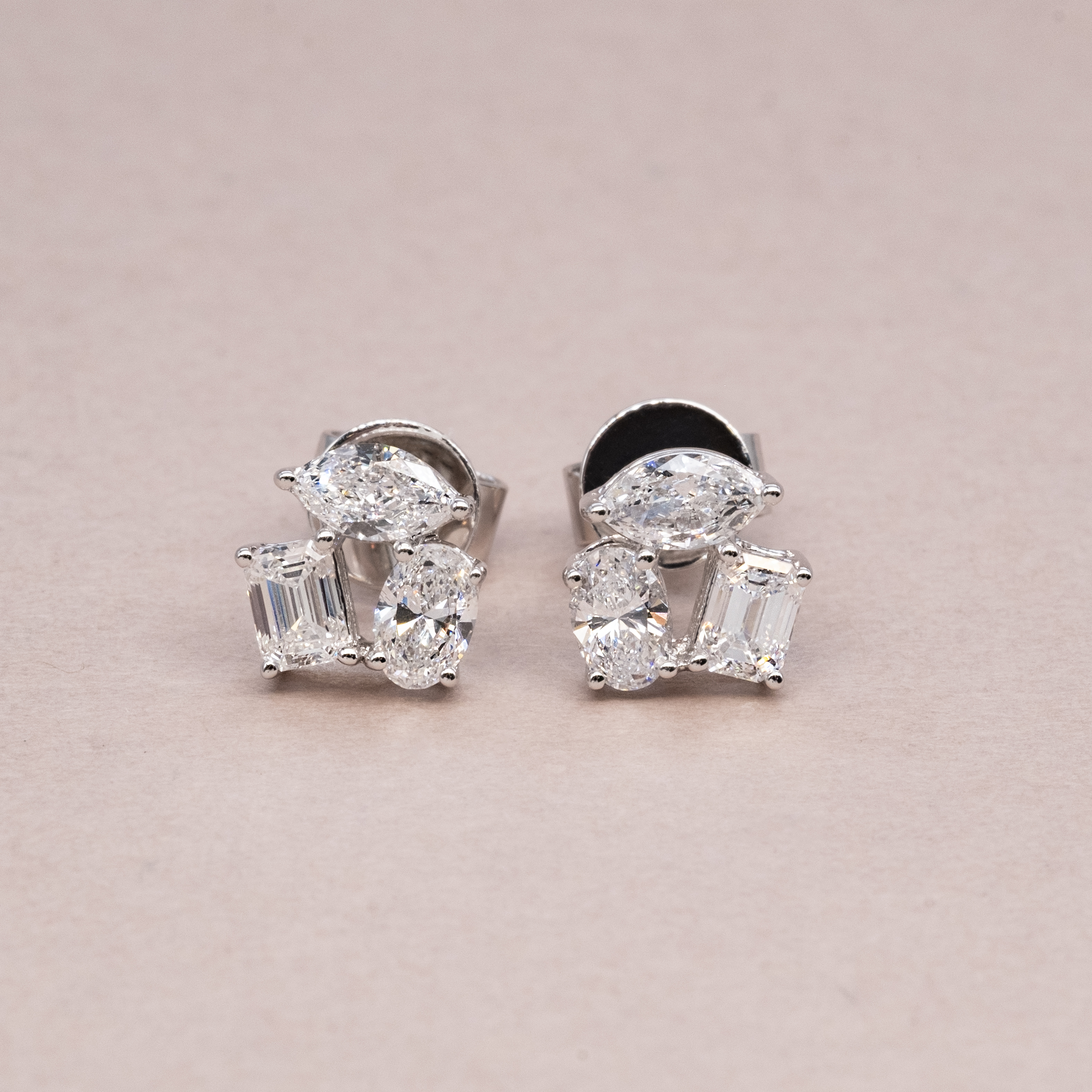 Front view of multi-shape diamond cluster stud earrings featuring marquise, oval, and emerald cuts