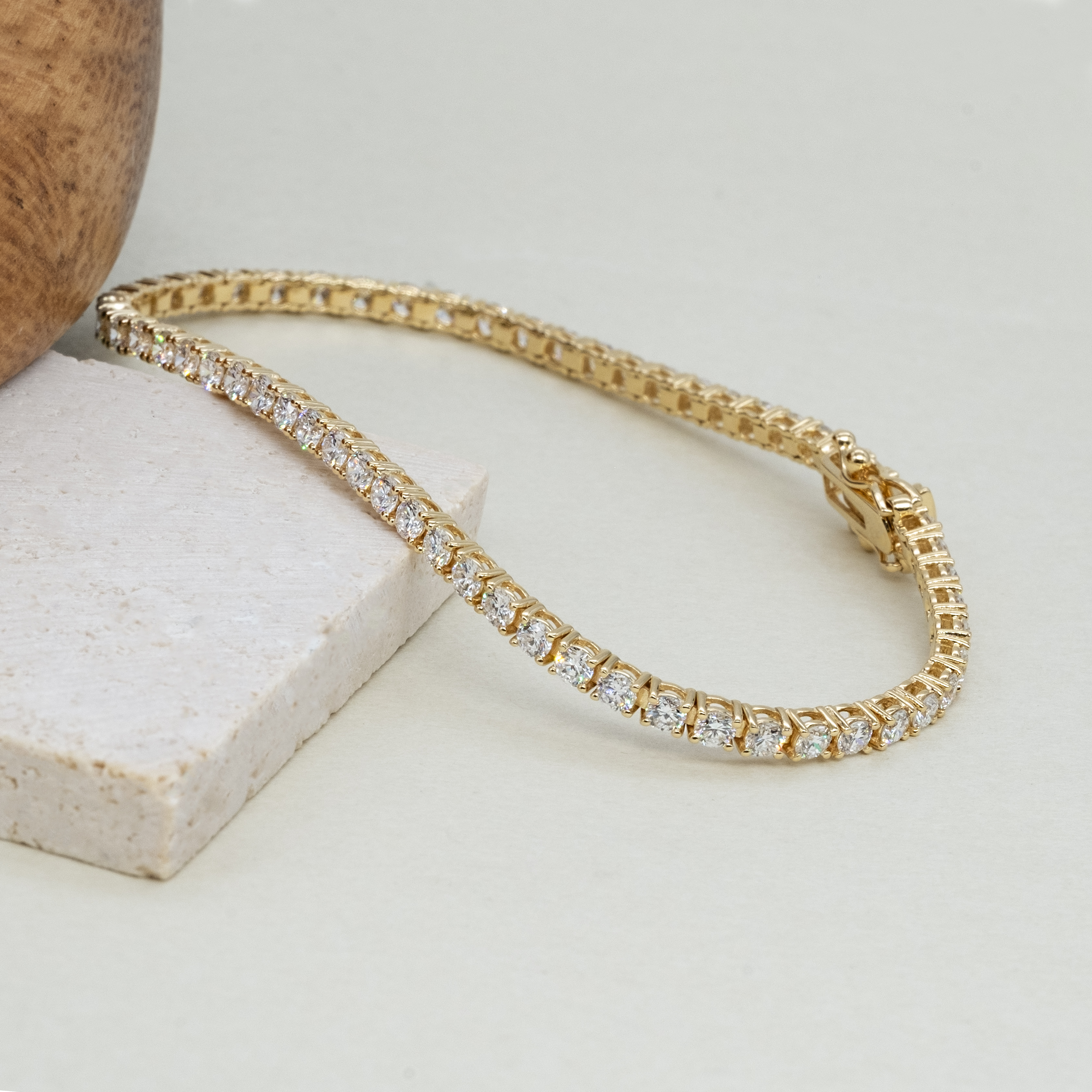 Close up of 2.8ct lab grown diamond tennis bracelet showing 2.3mm four prong setting 18k yellow gold