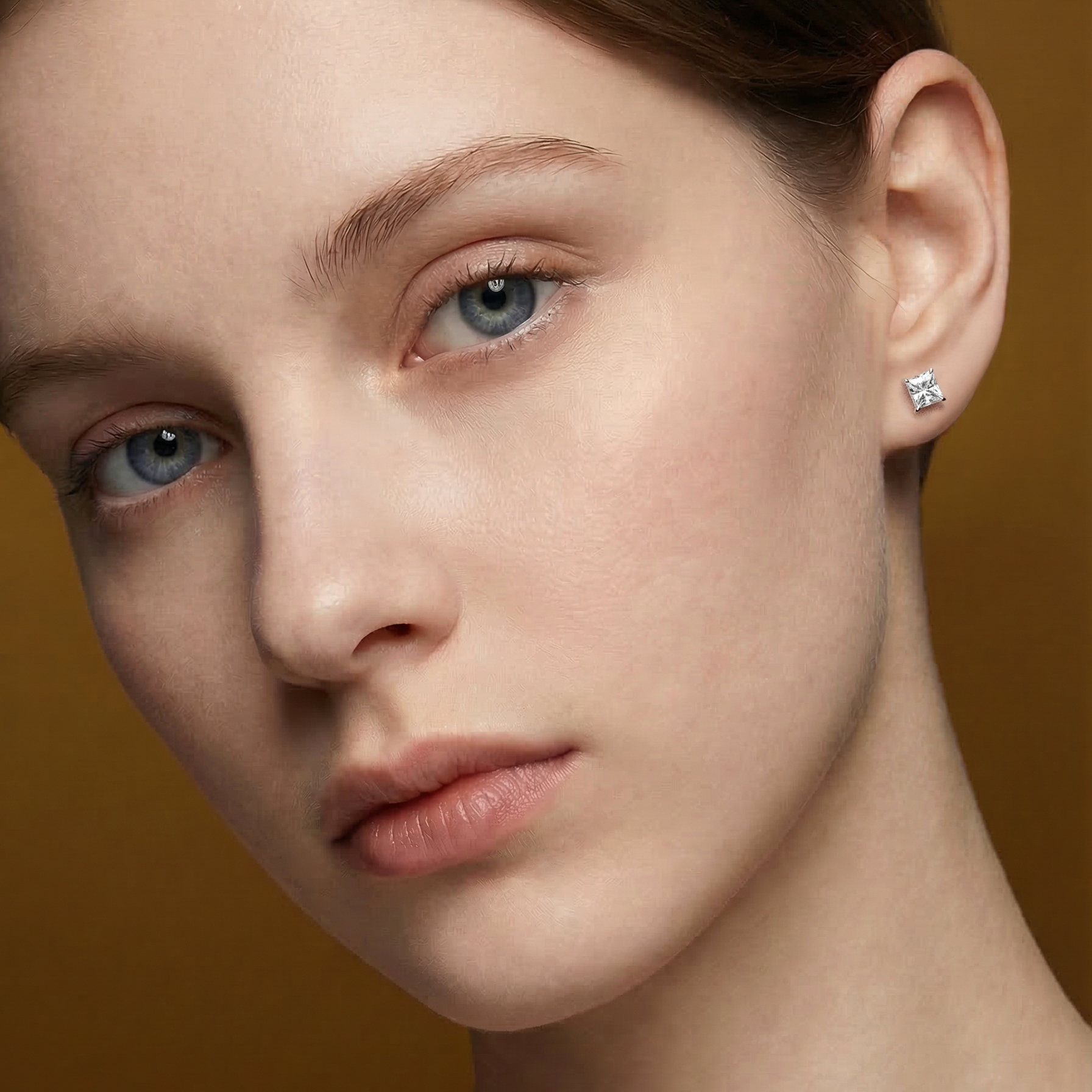 模特兒佩戴單邊 1 克拉公主方形培育鑽石耳環的實穿近拍。俐落的方形輪廓（Princess Cut）完美貼合耳垂，展現出現代女性獨立自信的氣質。1 克拉的份量感在耳畔極具存在感，光線折射出銳利而耀眼的火彩。