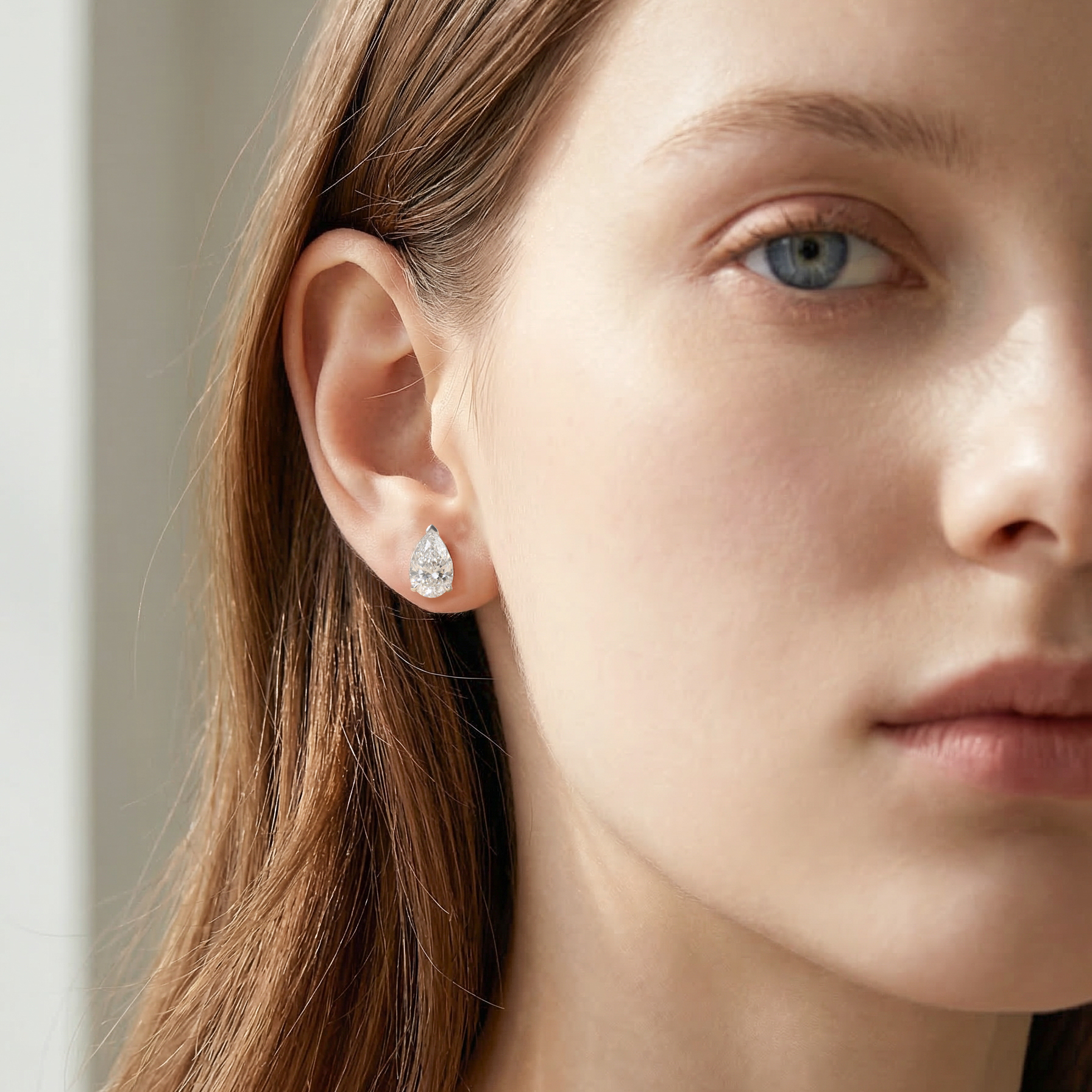 模特兒佩戴單邊 1 克拉水滴形培育鑽石耳環的實穿近拍。尖端朝上的水滴形（Pear Cut）設計完美貼合耳垂，1 克拉的大份量感在視覺上極具震撼力，同時能優雅地拉長頸部與修飾臉部輪廓，展現不凡的高級珠寶氣場。