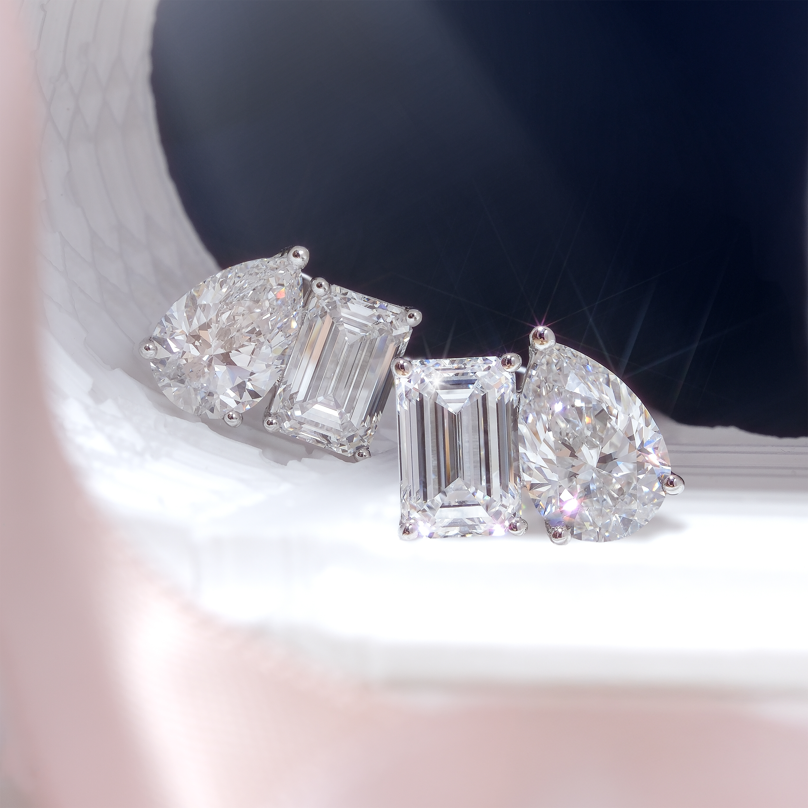 DIABOND Toi Et Moi 雙主石培育鑽石耳環平放特寫。展現了極具巧思的異形鑽石混搭：一側為閃耀圓潤的水滴形切割 (Pear Cut)，另一側為復古清透的祖母綠形切割 (Emerald Cut)。四顆鑽石皆為頂級 D 色、重約 1 克拉，在 18K 白金的鑲嵌下，散發出截然不同卻又完美和諧的極致火彩。