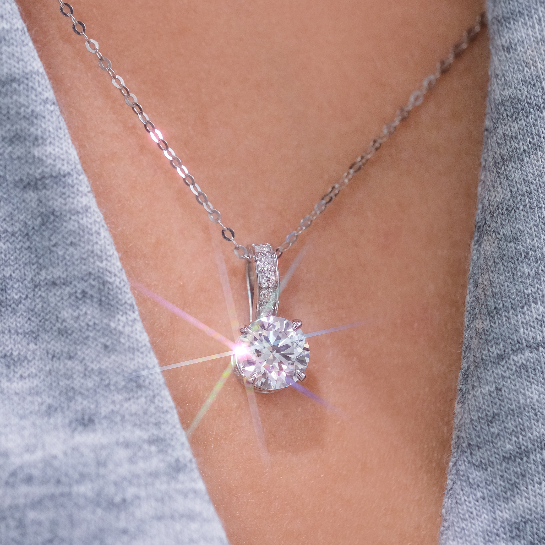 模特兒佩戴 1 克拉隱藏光環培育鑽石吊墜頸鏈的實穿展示。可調式 18K 金鏈條完美垂墜於鎖骨之間,1 克拉的份量感在日常穿搭中極具存在感。密釘鑲嵌的扣環細節增添了整體造型的精緻度與奢華層次。