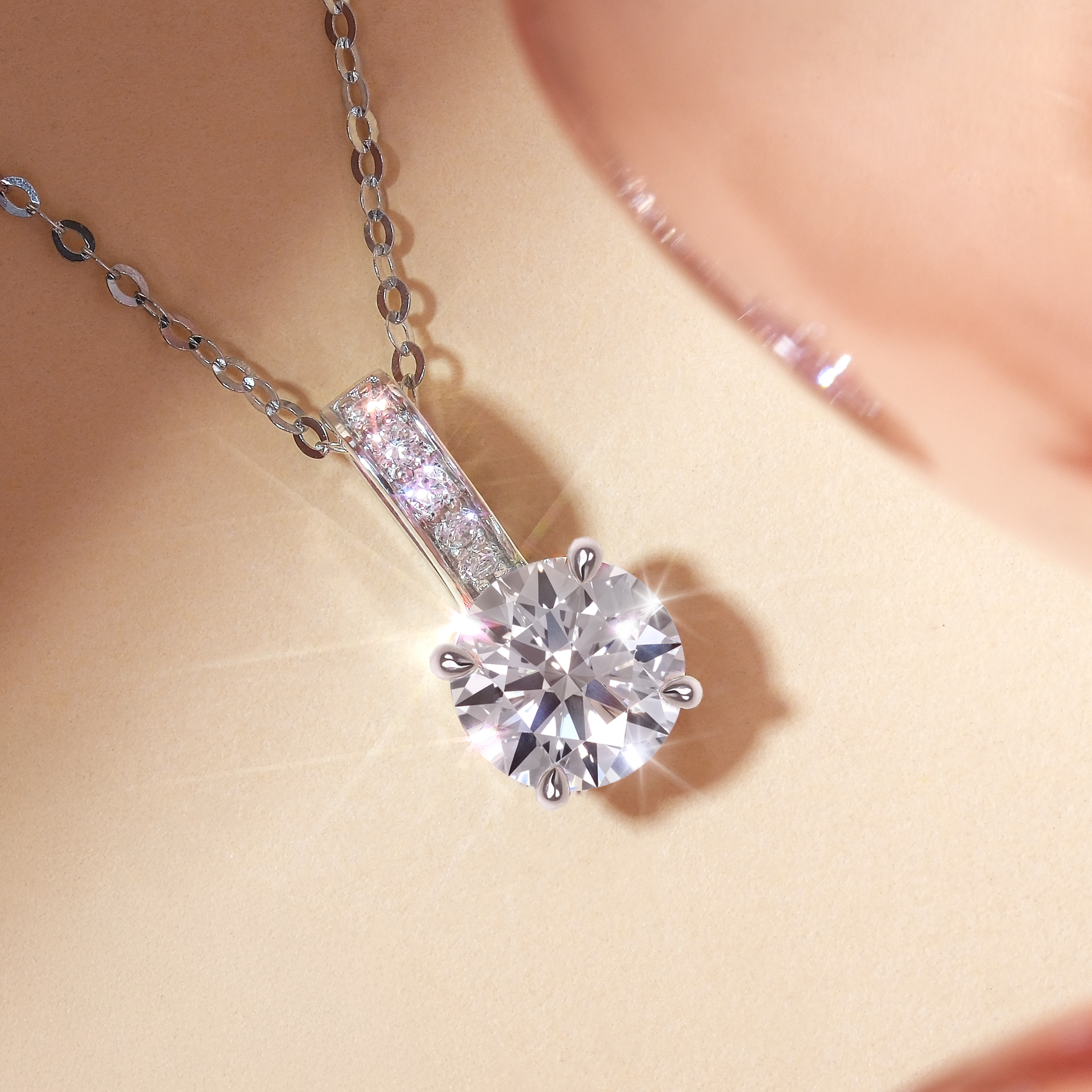 1 克拉圓形培育鑽石吊墜正面近拍展示。頂級 D 色、VS 淨度的主鑽在光線下折射出令人屏息的十字星芒與耀眼火彩。吊墜頂部的扣環鑲滿共 0.15 克拉的璀璨副鑽，與主石相互輝映，搭配細緻的 18K 白金鏈條，展現高貴典雅的氣質。