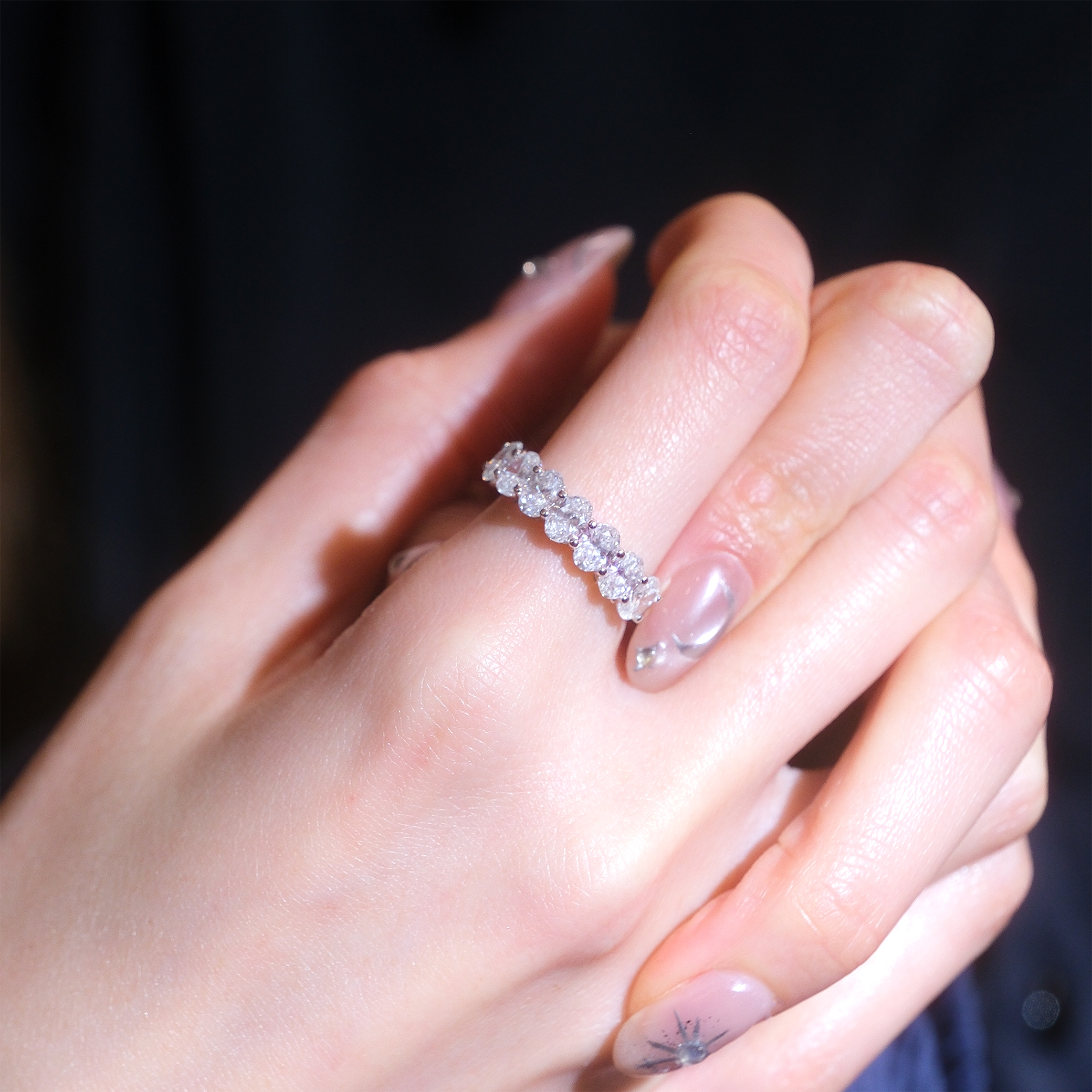 模特兒單獨佩戴 2.1 克拉七粒橢圓形培育鑽石戒指的實穿近拍。橢圓形切割的鑽石打橫排列，寬度達 2.5mm，完美覆蓋手指的正面視覺範圍。即使單獨佩戴也極具份量感，展現高貴優雅的氣質。