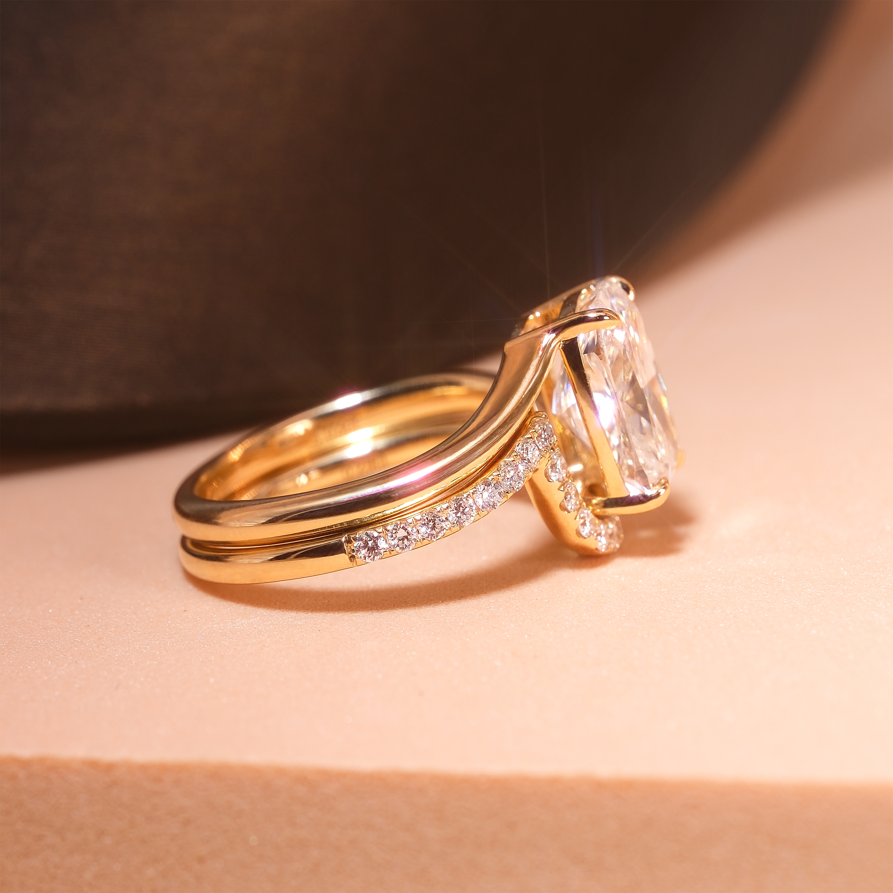 DIABOND 3.03ct 枕形培育鑽石 18K 黃金套裝婚戒側面立體展示。清晰可見主戒四爪簡約鑲嵌將枕形主鑽高托，弧形排鑽配戒（Contour Band）以精準計算的流線弧度緊貼主戒下方，兩枚戒指合體呈現完美的一體感。