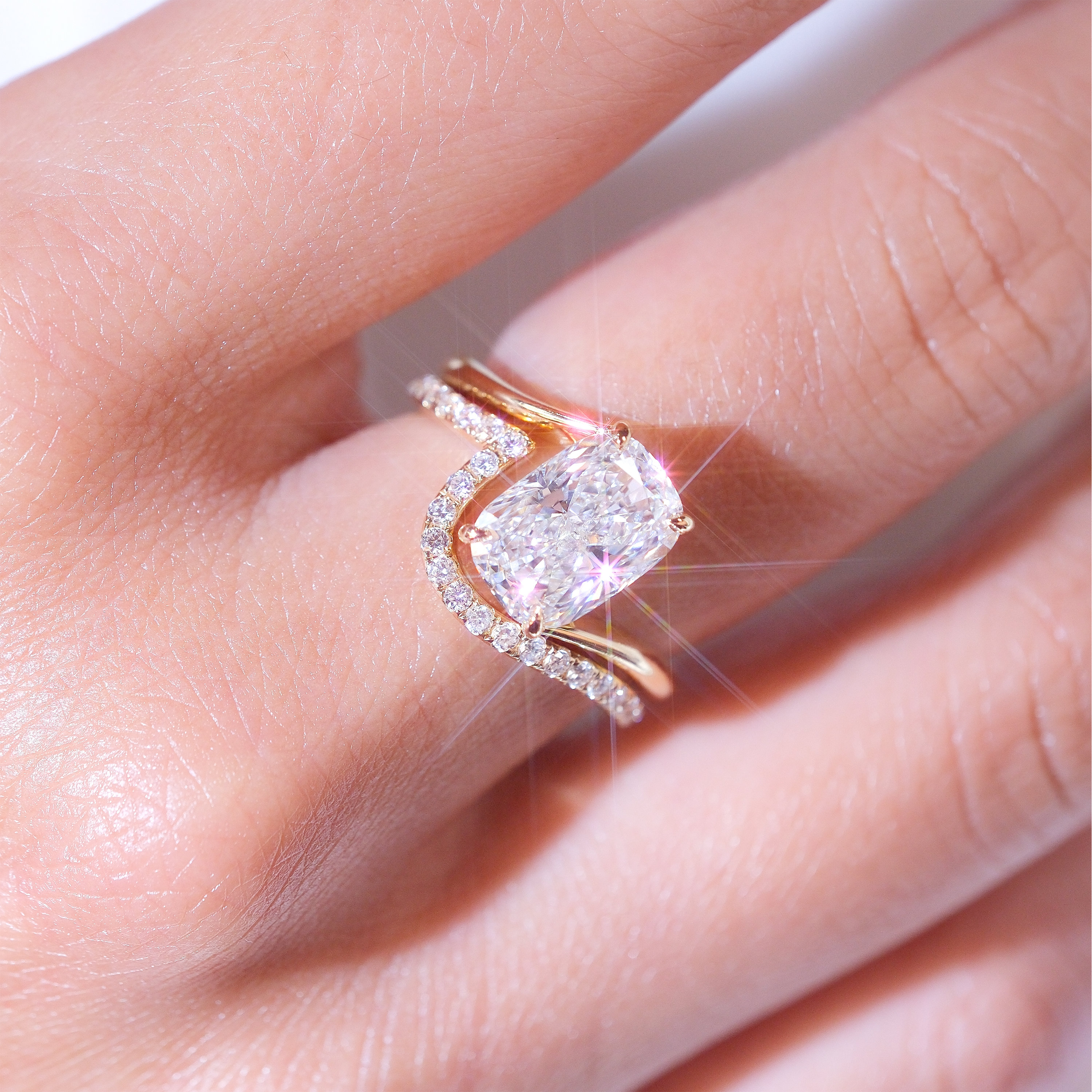 模特兒手部特寫展示 DIABOND 3.03ct D/VVS2 枕形培育鑽石套裝婚戒。枕形主鑽在光線下爆發耀眼十字星芒，下方弧形排鑽配戒（Contour Band）以流線型完美貼合主戒底部。18K 黃金暖色調與純白鑽石形成絕美對比，附 IGI 國際認可證書。