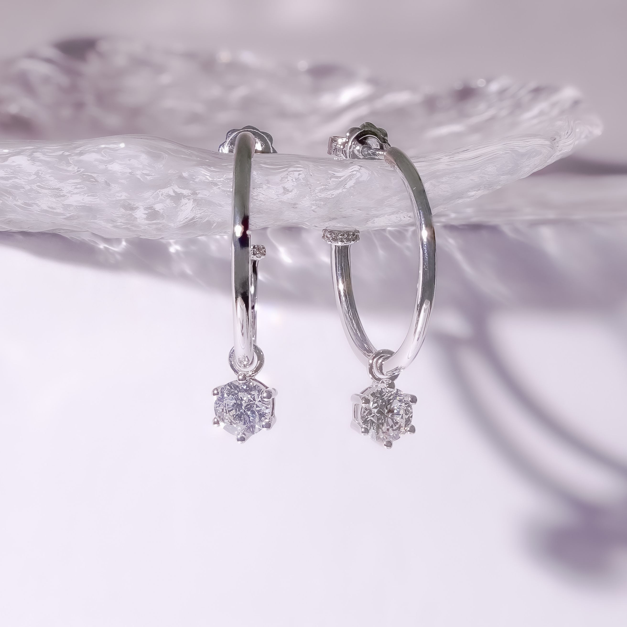 18k white gold hoop earrings featuring dangling 1ct solitaire diamonds.