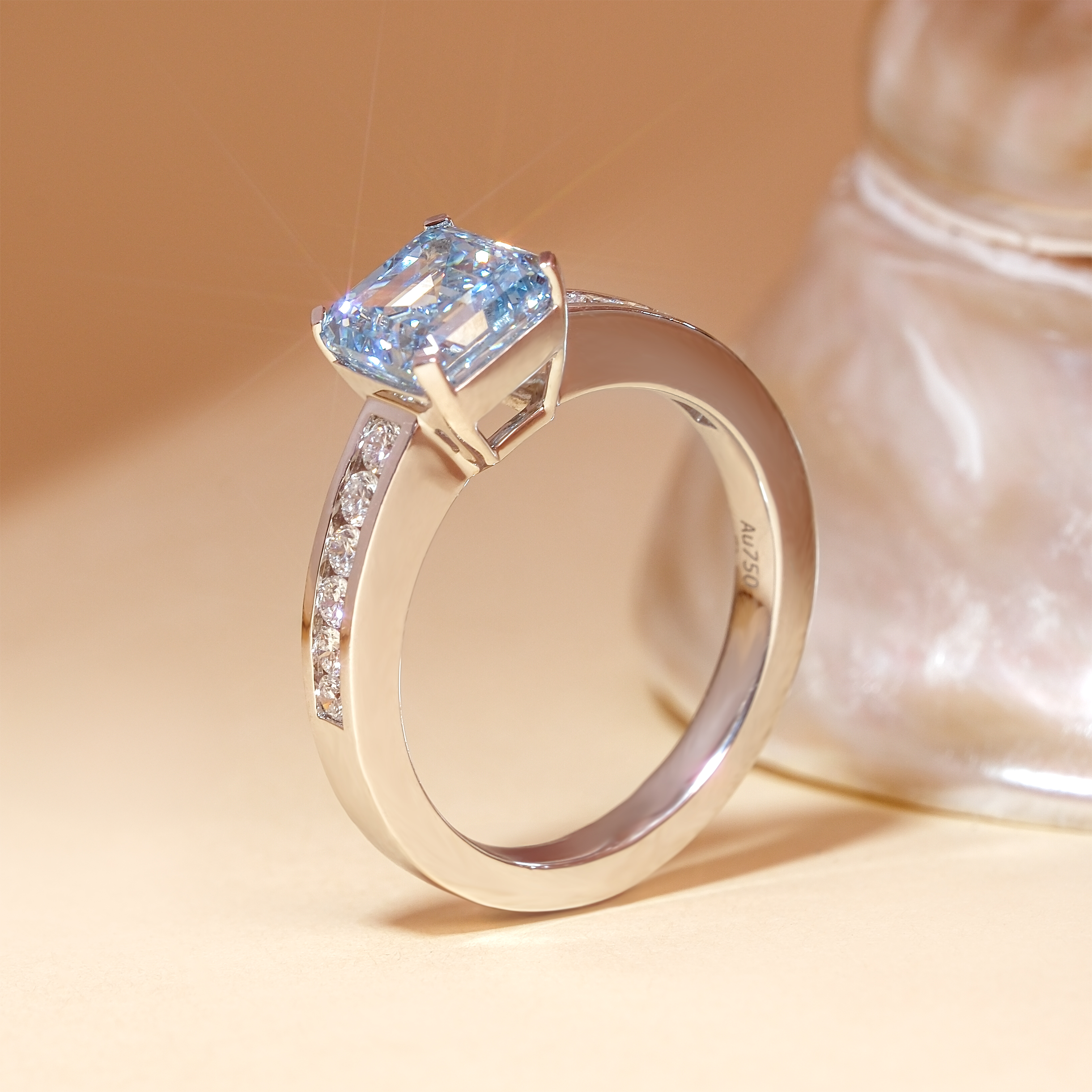 2.01 克拉阿斯切形培育藍鑽戒指的側面立體展示。清晰可見 18K 白金厚實且流暢的戒台設計，以及專為阿斯切方鑽打造的四爪鑲座。戒臂兩側的槽鑲白鑽整齊排列，完美演繹了裝飾藝術 (Art Deco) 時期充滿建築感的俐落線條與幾何美學。