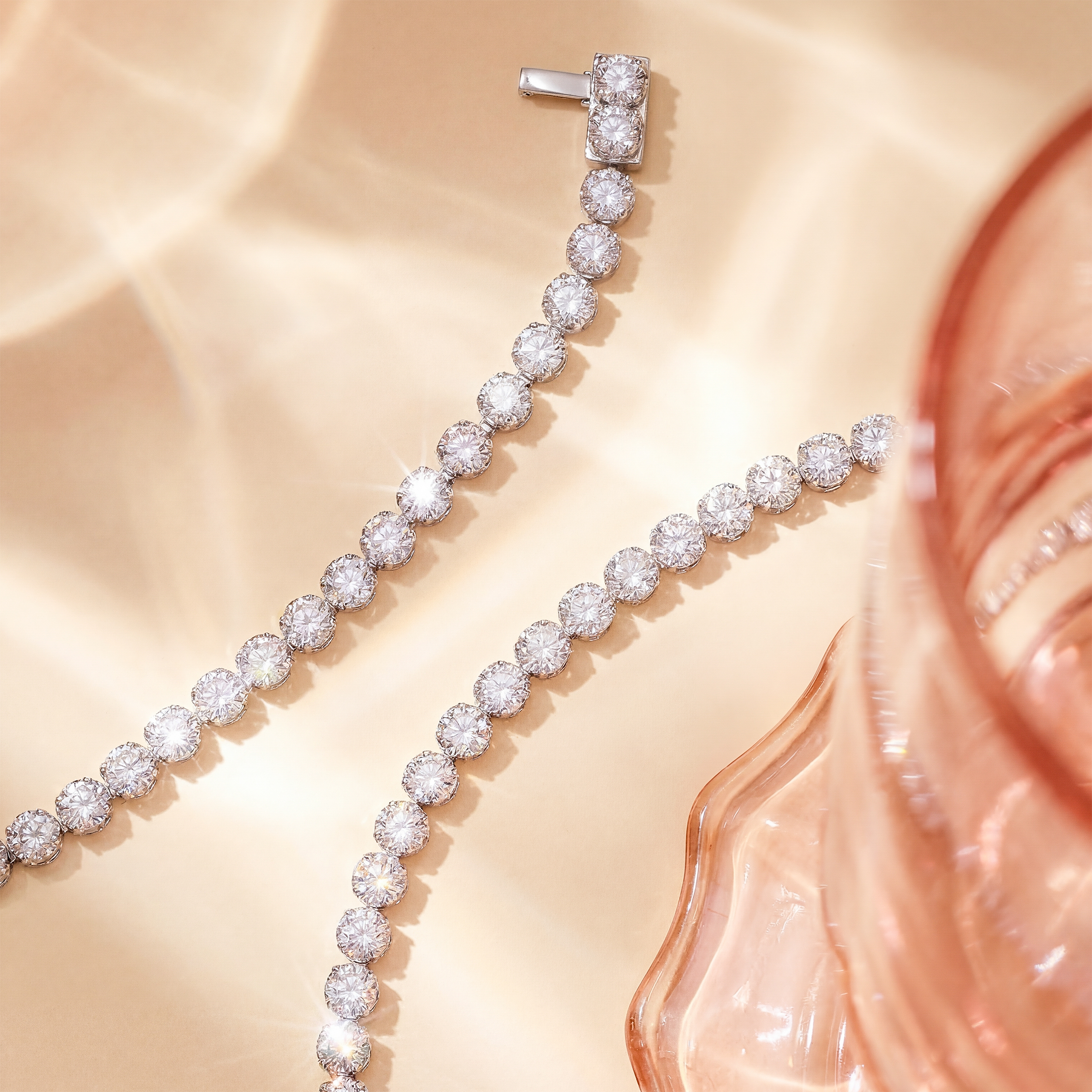 近拍展示 20.66 克拉培育鑽石網球頸鏈的高級珠寶細節。清晰可見採用堅固的 PT750 鉑金打造的經典四爪鑲嵌 (Prong Setting)，以及隱藏式的雙重安全插扣設計 (Box Clasp)。確保每顆 0.2 克拉的閃爍美鑽都能完美排列，同時提供極致安全的佩戴體驗。

