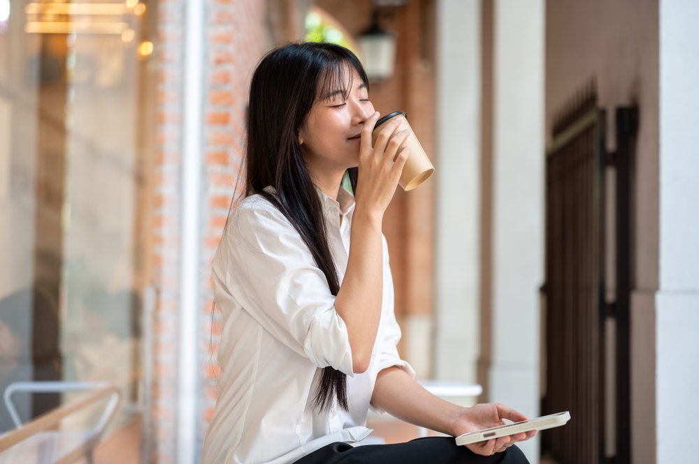 พนักงานออฟฟิศหญิงดื่มเครื่องดื่มที่มีคาเฟอีนหลังทำงานเหนื่อยช่วงเช้า