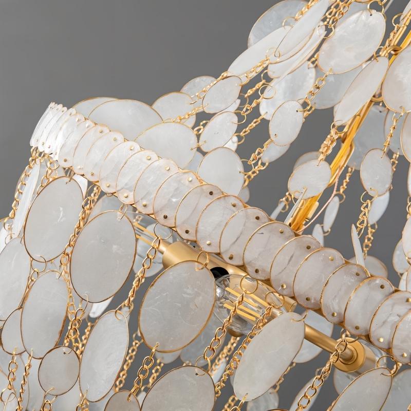 "Close-up of a tiered chandelier with cascading natural shell elements, gold frame, and gold chains."