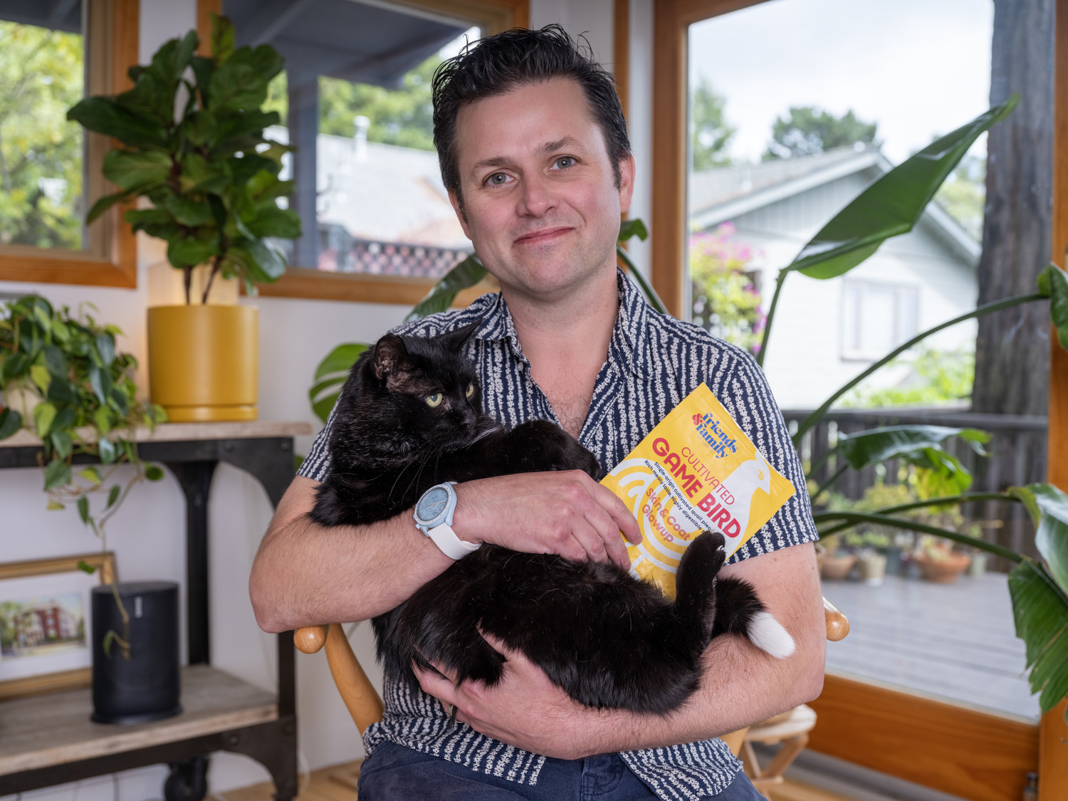Founder Joshua Errett holds up the worlds-first cultivated meat treats for cats, along with his cat Boston