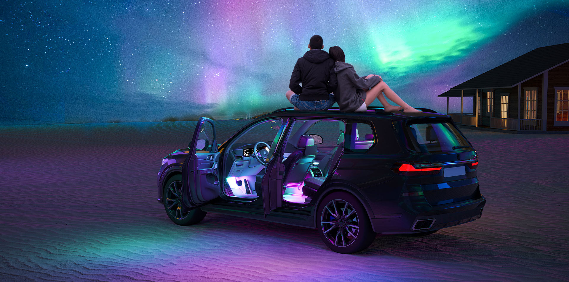 a couple of people sitting on a car in a driveway with a starry sky above