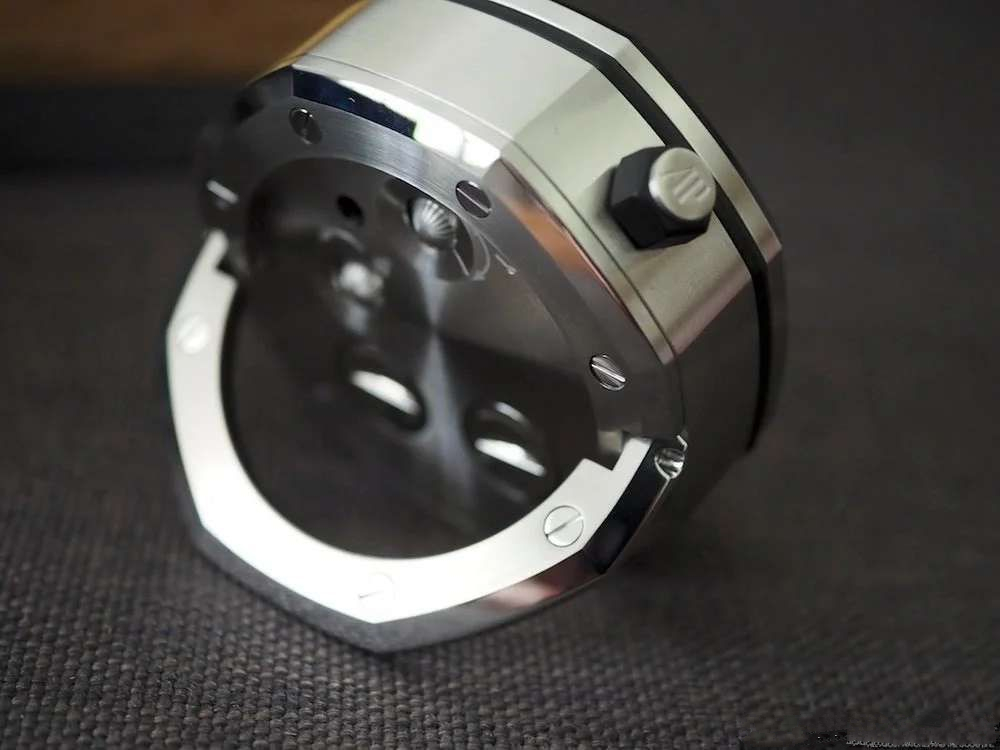 TZ爱彼皇家橡树系列15710款专卖店座钟/小桌钟，办公室、书房、驾驶室的灵魂点缀。购置原装开模，和原装一样为65mm*26mm规格，深度还原15710的格纹字面和颗粒效果，一比一比等比放大字面，原单级别的字面填油和内影工艺，进口石英机芯，夜光指针，实心316L精钢打造，重量同等于原装，做工丝毫不逊色于原装。可放置在实木木托上，亦可独立背部支撑。 【使用方法】 ➀调节时间：先找到背部对应9点钟位置的旋钮，然后用拇指和食指捏住旋钮，最后拧动旋钮调至当前时间。 ➁设置闹钟：首先找到背部对应3点钟位置的旋钮，然