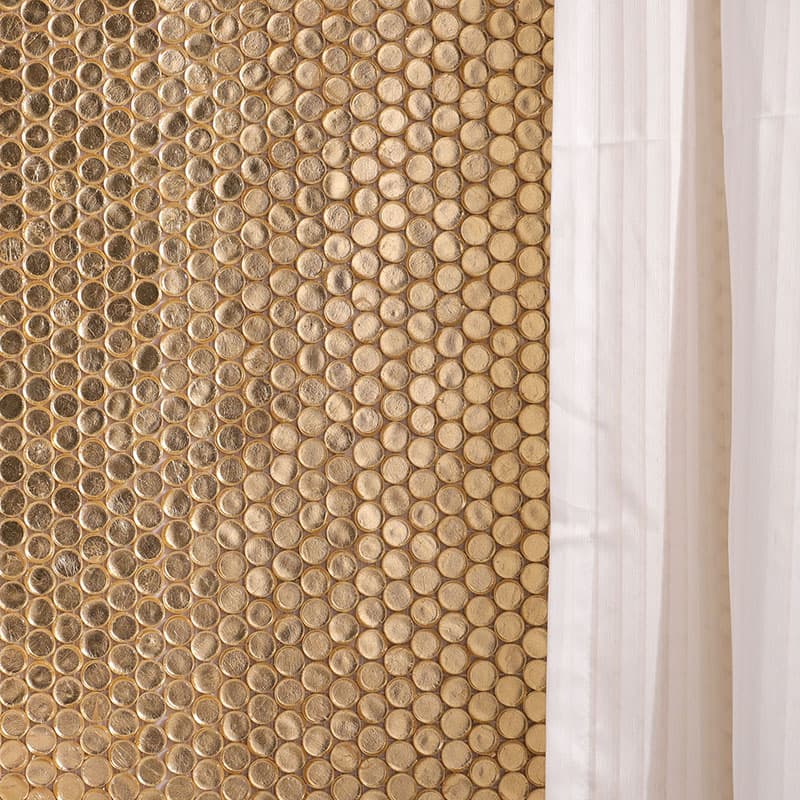 白いタオルとランコムの泡ボトルを配した、金色ガラス円形モザイクタイルのバスルーム壁面