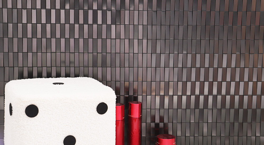 {"default":"ダークカラーのリビングタイル壁と白いスツール、赤いボトルが映えるモダン空間"}
