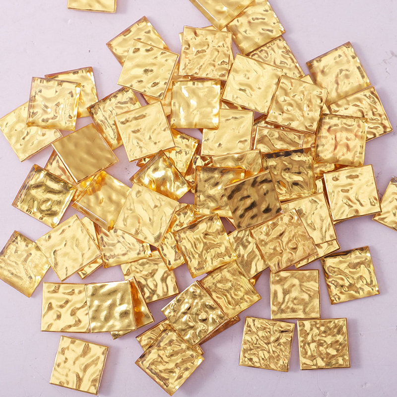 複数の金色四角モザイクタイルがランダムに広げられた様子の写真