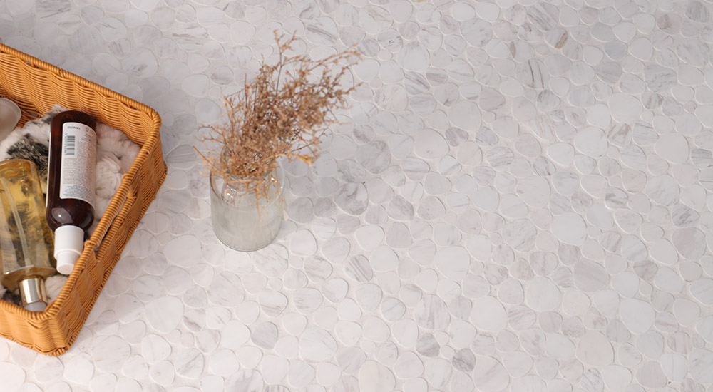 {"default":"割石タイル風の白い小石調タイル床と、バスルームに置かれたバスケット小物のイメージ"}
