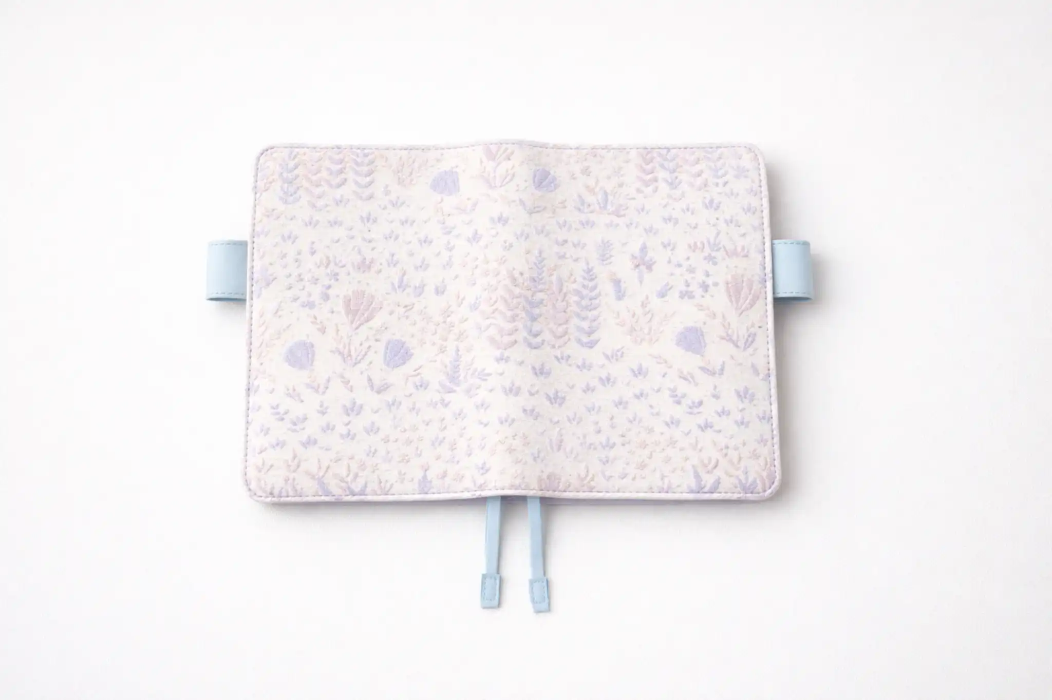 ABIGALECrafts pastel purple botanical embroidered cover in a flat lay view, highlighting the light blue pen loops and textured fabric.
