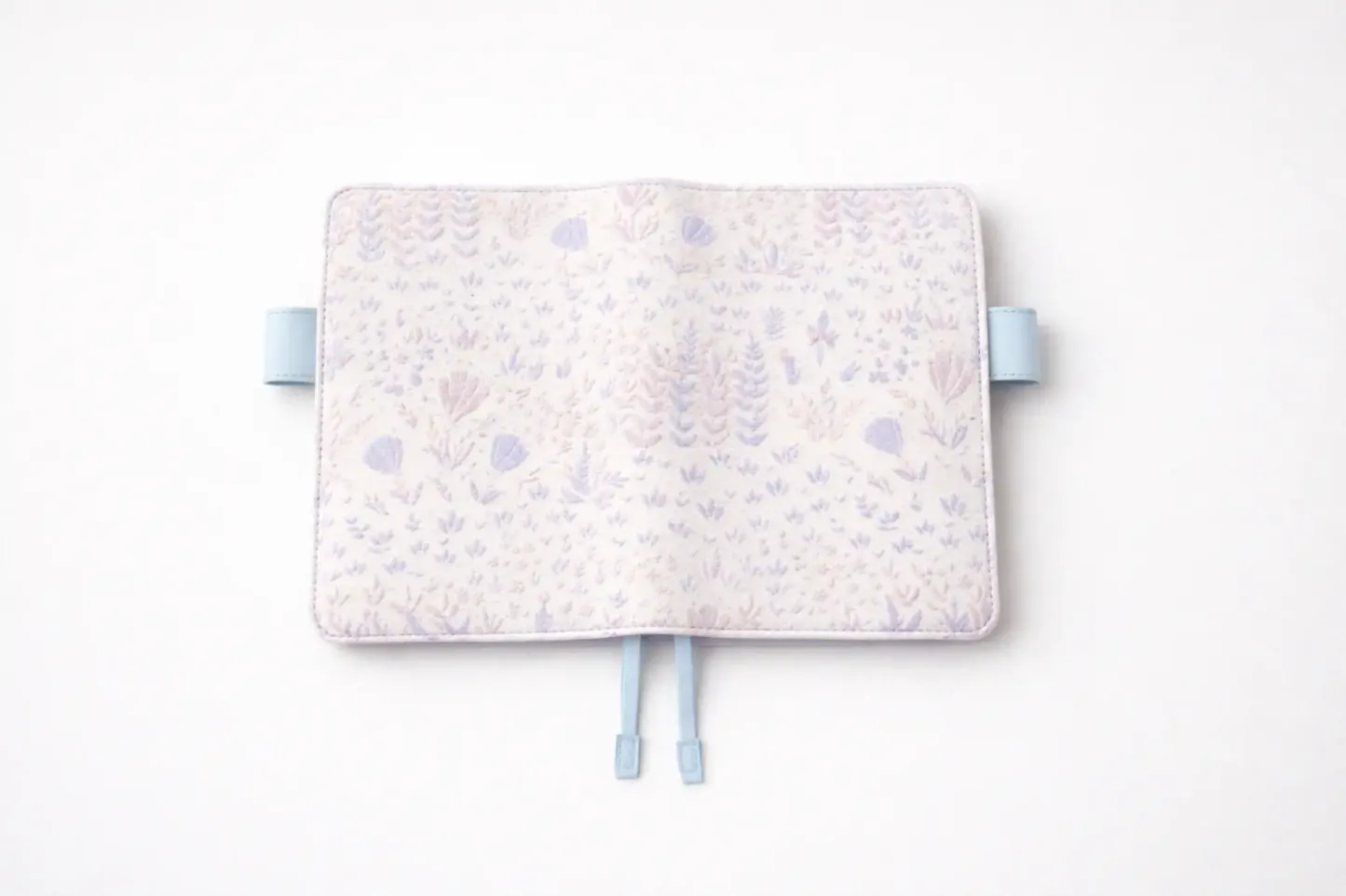 ABIGALECrafts pastel purple botanical embroidered cover in a flat lay view, highlighting the light blue pen loops and textured fabric.