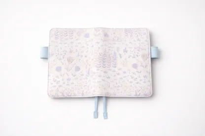 ABIGALECrafts pastel purple botanical embroidered cover in a flat lay view, highlighting the light blue pen loops and textured fabric.