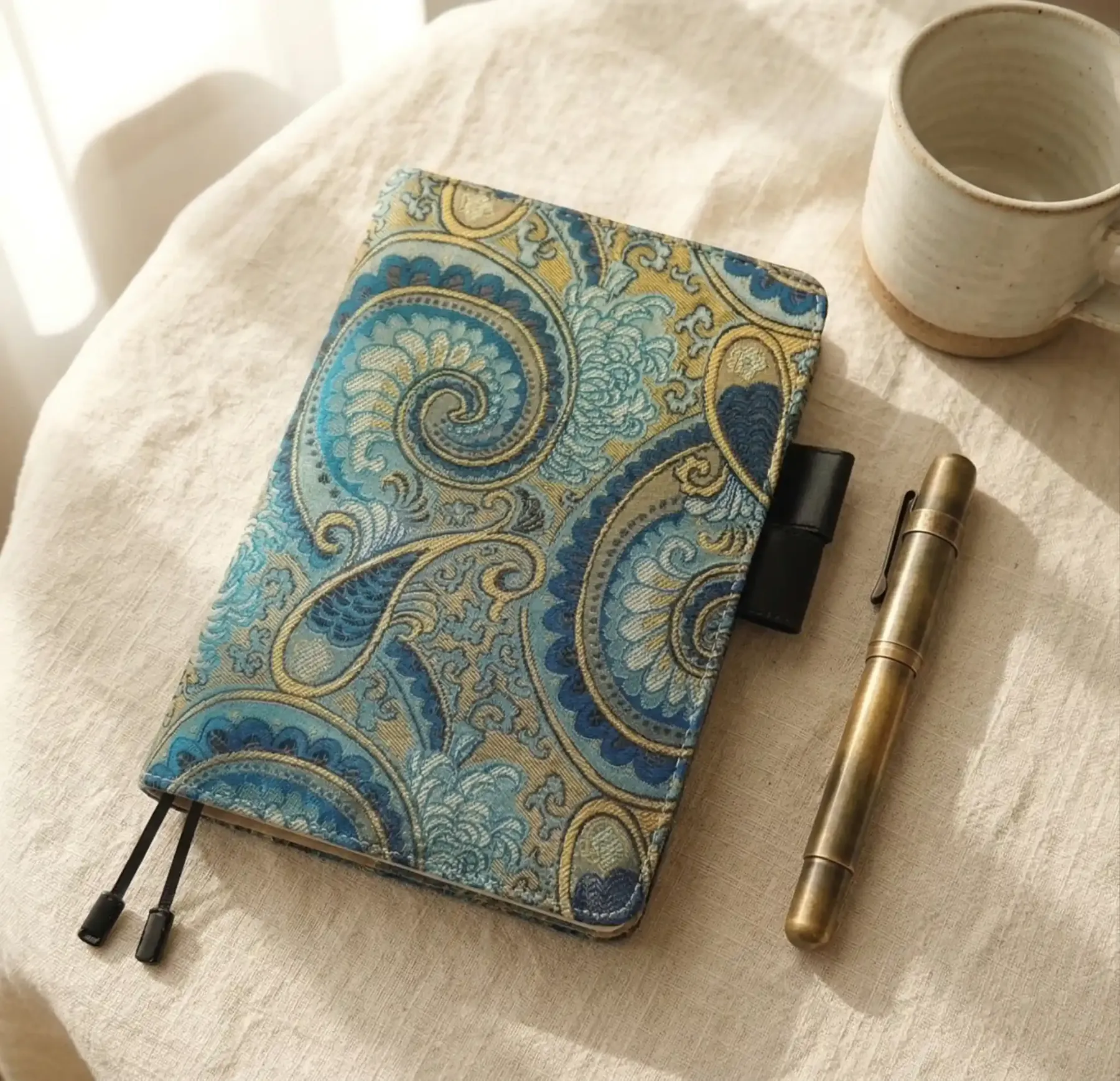 Aesthetic desk setup with an A5 organizer cover styled for Hobonichi Cousin, paired with a brass pen and mug.