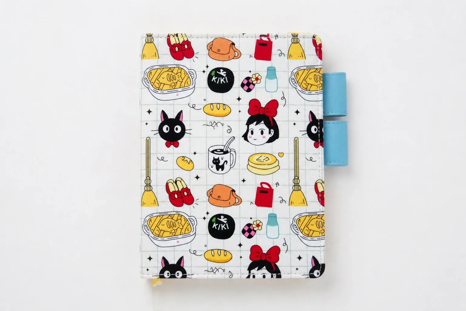 Front view of a black cat and broomstick print planner cover with bakery motifs and blue pen loops against a white background.