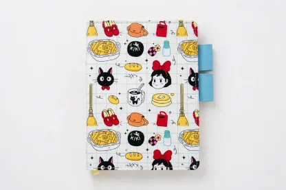 Front view of a black cat and broomstick print planner cover with bakery motifs and blue pen loops against a white background.