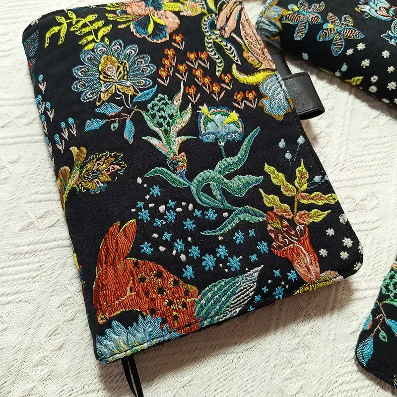 Close-up front view of black floral and rabbit embroidered planner cover