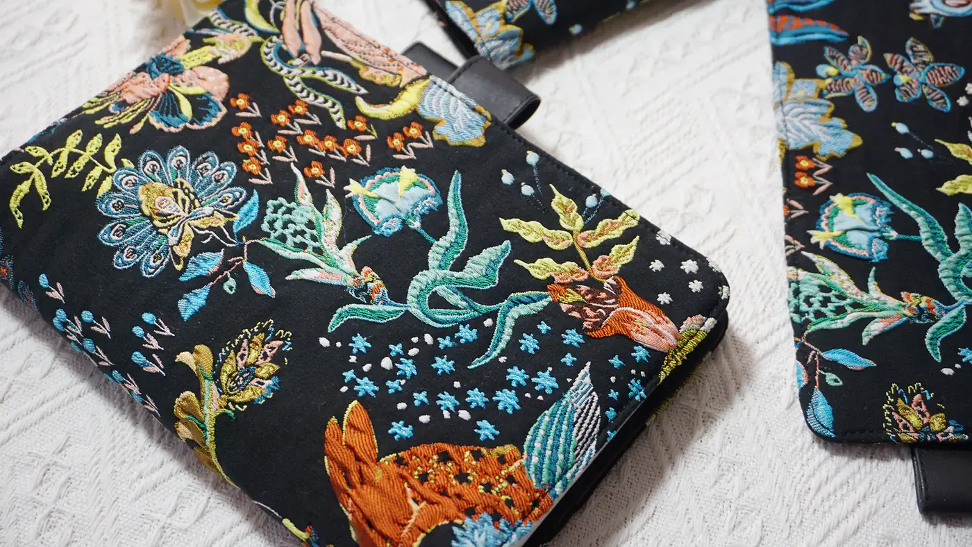 Close-up of colorful floral and rabbit embroidery on a black planner cover