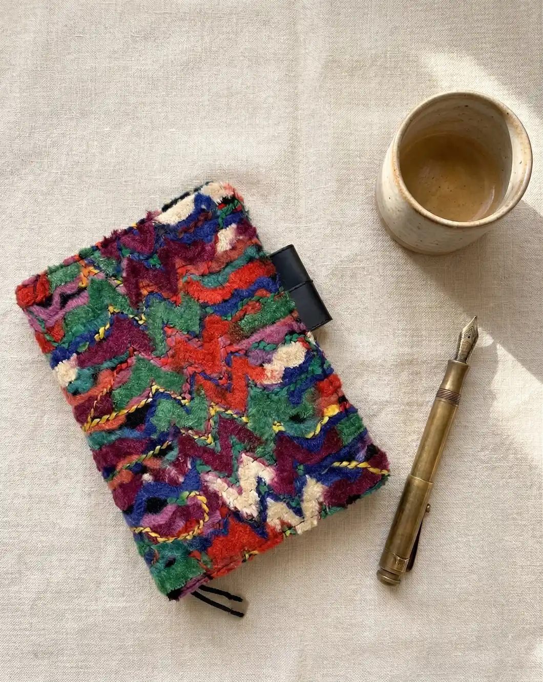 Colorful boho embroidered Hobonichi Cousin A5 cover on linen background with brass fountain pen and coffee.
