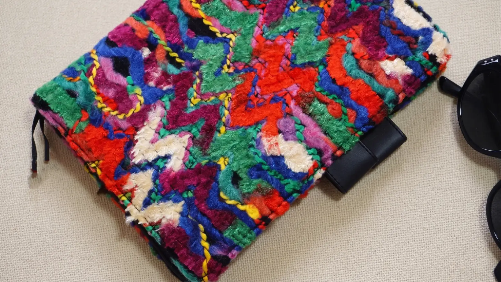 Close-up of textured multi-color woven notebook sleeve fit for Hobonichi with black leather pen loop.