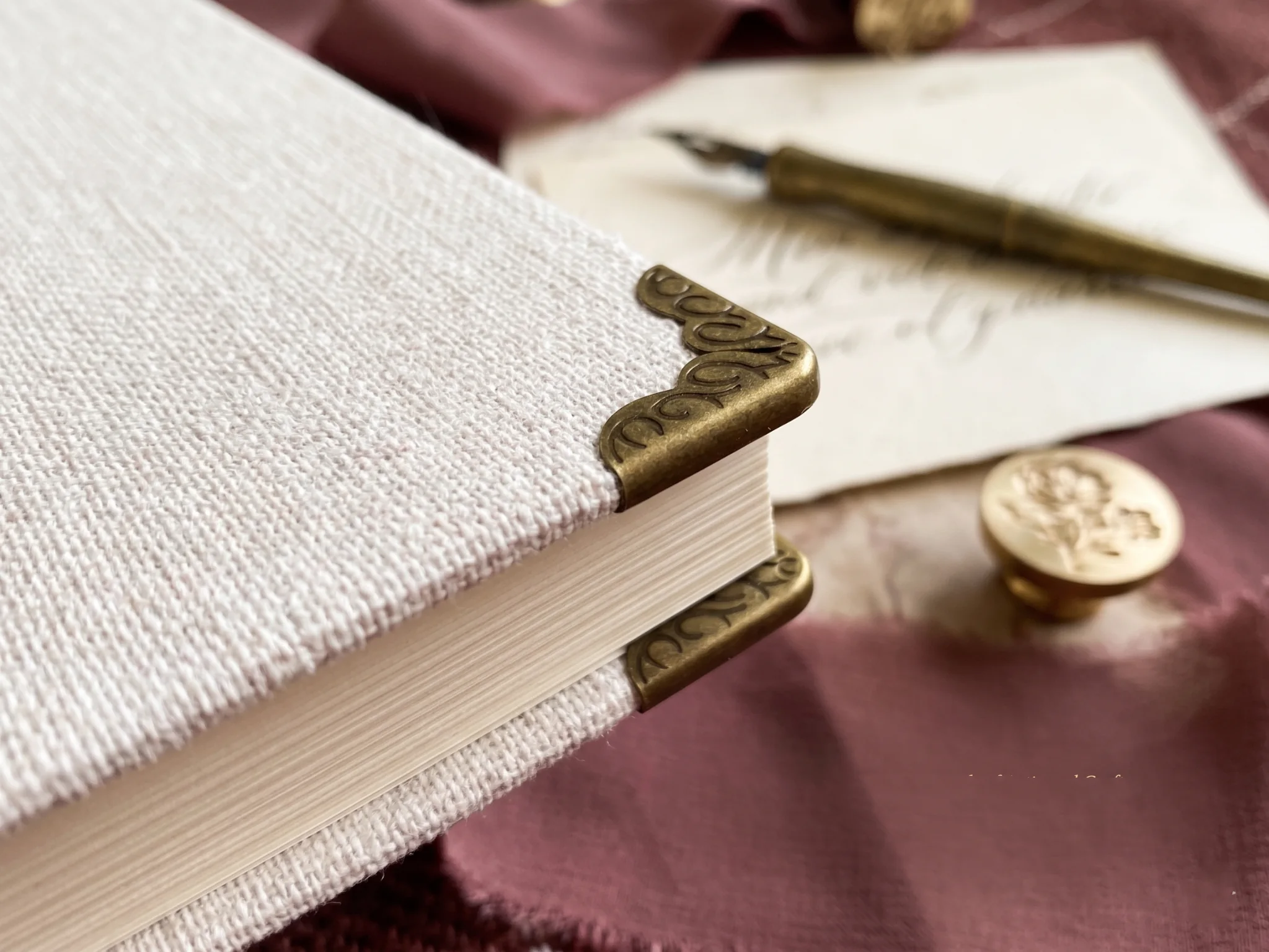 Close-up of handcrafted linen wedding vow book with vintage copper corner protectors