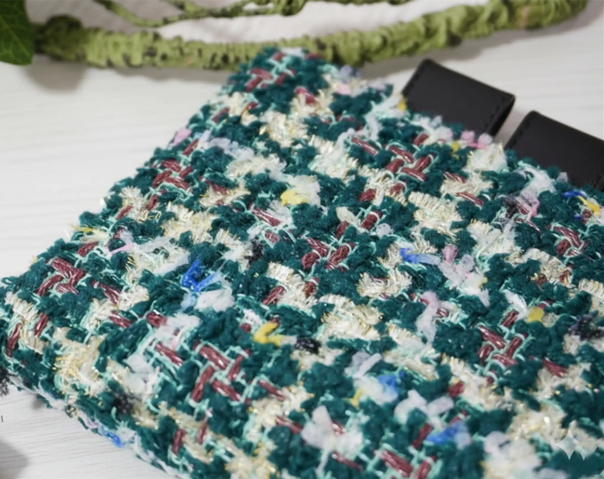 Close-up of green woven tweed texture and black leather pen loop for Hobonichi.