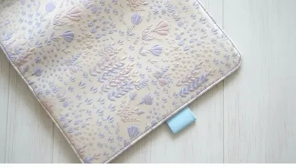 Close-up of the light blue leather-style pen loop and durable stitched edge details on an ABIGALECrafts embroidered notebook cover.