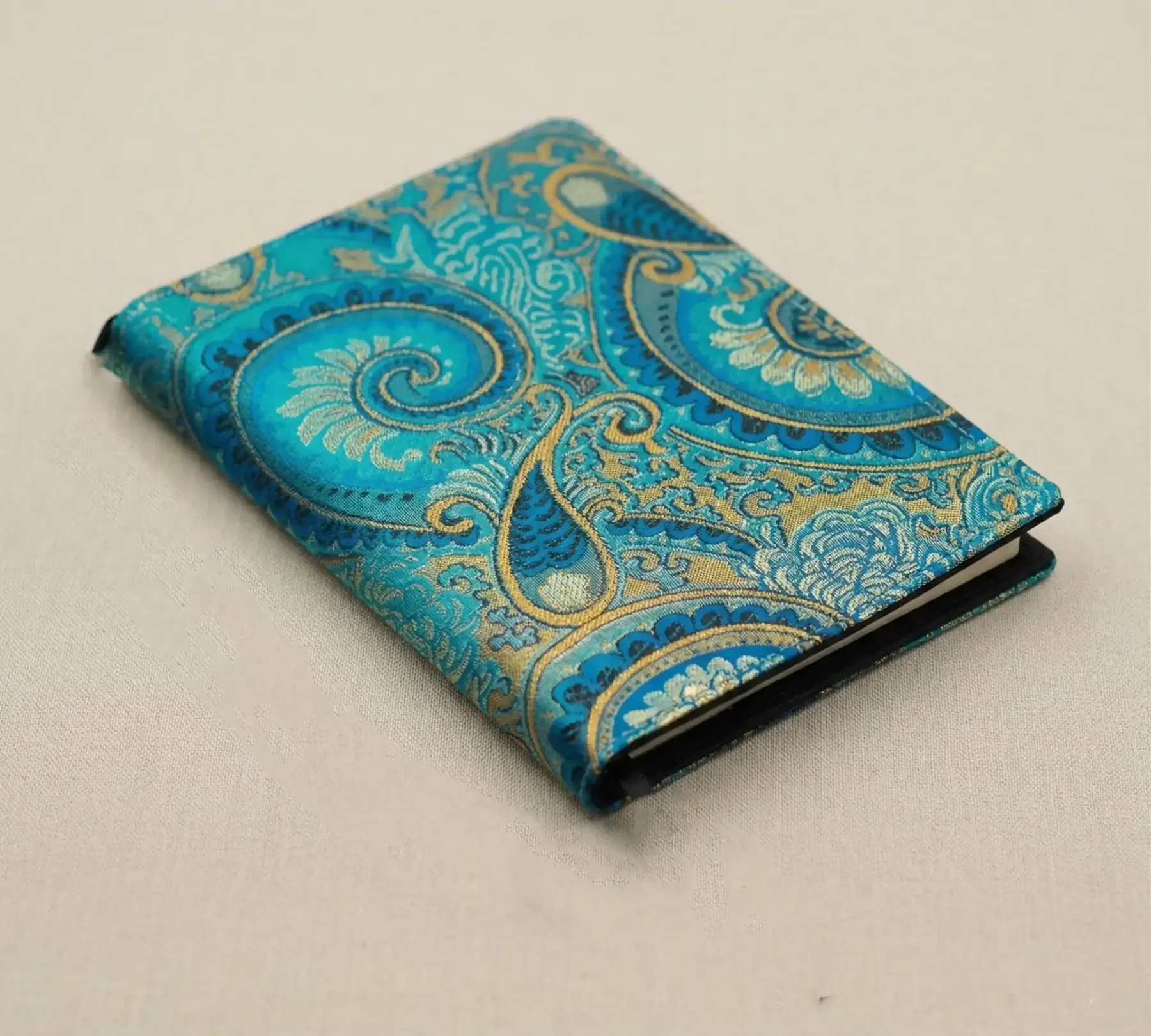 Side profile of a woven textile journal case compatible with Hobonichi A6 Planner, showing thickness