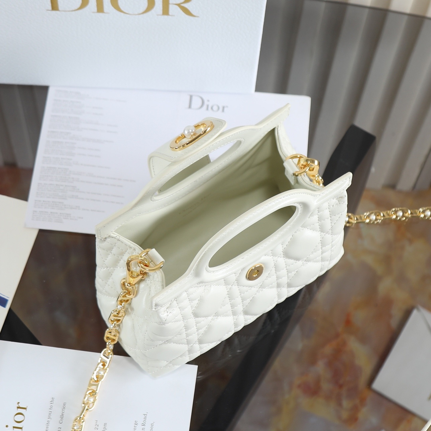 原廠級 白色鏈條手袋
這款 Dior Jolie Top Handle 迷你鏈條手袋是二零二六早春成衣系列新品，呈現出優雅精緻的設計。採用黑色羊皮革精心製作，飾以藤格紋，翻蓋點綴以金色飾面金屬 CD 標誌和白色樹脂珠飾。內設一個隔層，可收納各種日常用品。搭配雙頂部手柄和可調節、可拆卸 CD 鏈條肩帶，肩帶由皮革帶和 CD 鏈環組成，飾以白色樹脂珠飾，可舒適手提、肩背或斜挎，可與日常或晚裝造型搭配。
