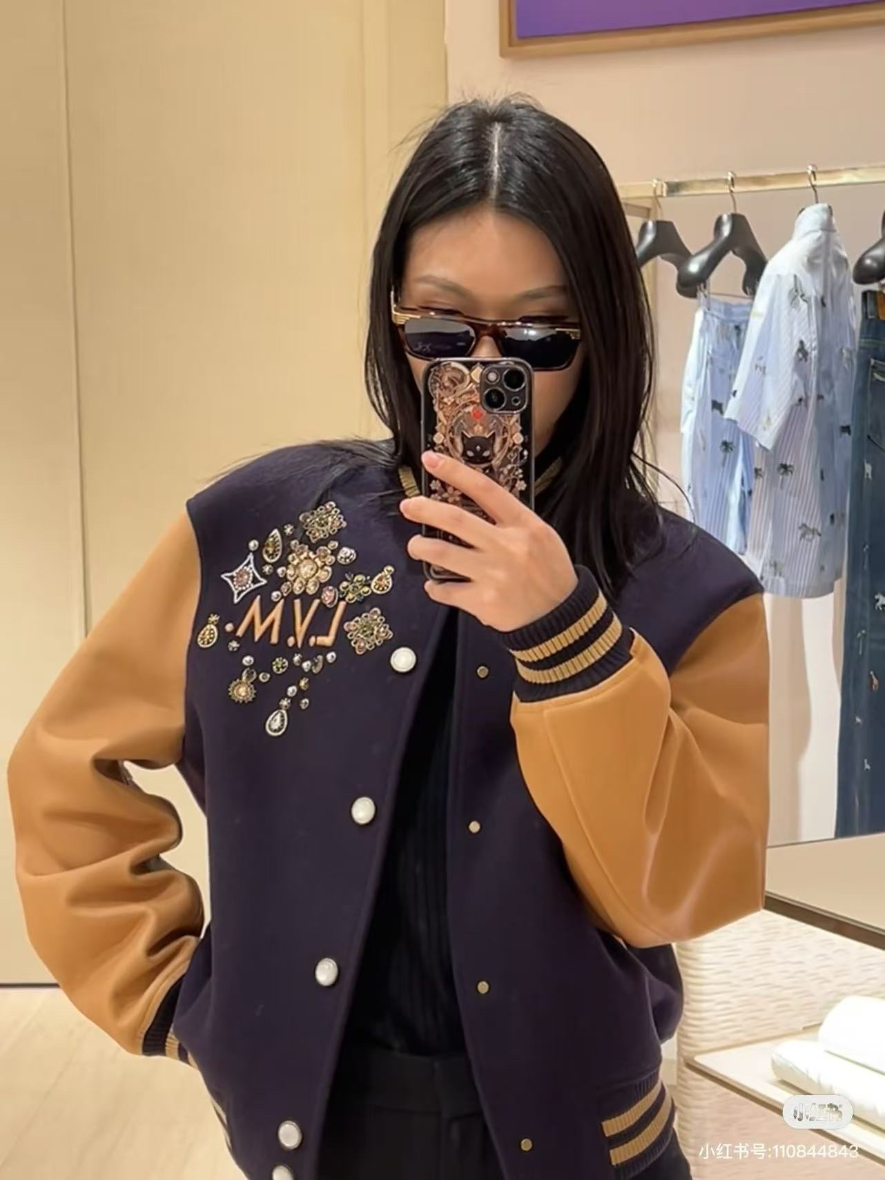 Louis Vuitton/路易威登 26ss 水鑽刺繡棒球服外套
材質拼接：衣身採用藏青色羊毛混紡面料，質感挺括耐磨；袖子為淺棕牛皮材質，柔軟細膩，經典拼皮設計還原美式棒球服復古感。

• 裝飾亮點：左胸位置有重工水鑽+金屬刺繡裝飾，鑲嵌多色寶石與閃鑽，綴有“L.V.M.”字母標識，華麗精緻，辨識度拉滿。

• 版型結構：立領+羅紋條紋領口/袖口/下擺，防風且修飾身形；正面按扣開合，兩側配有插袋，兼顧實用與美觀。
球帽點綴，休閒隨性又有街頭感。
N Size:S-XL