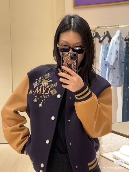 Louis Vuitton/路易威登 26ss 水鑽刺繡棒球服外套
材質拼接：衣身採用藏青色羊毛混紡面料，質感挺括耐磨；袖子為淺棕牛皮材質，柔軟細膩，經典拼皮設計還原美式棒球服復古感。

• 裝飾亮點：左胸位置有重工水鑽+金屬刺繡裝飾，鑲嵌多色寶石與閃鑽，綴有“L.V.M.”字母標識，華麗精緻，辨識度拉滿。

• 版型結構：立領+羅紋條紋領口/袖口/下擺，防風且修飾身形；正面按扣開合，兩側配有插袋，兼顧實用與美觀。
球帽點綴，休閒隨性又有街頭感。
N Size:S-XL