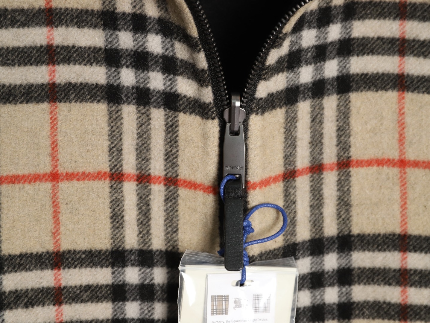 🔝BURBERRY巴寶莉BBR 雙面穿羊毛連帽外套
精選雙面羊毛斜紋面料，通過獨特的拉絨工藝處理，使表層呈現細膩豐盈的絨毛質感，觸感如雲朵般柔軟親膚，同時保留羊毛天然的保暖性與透氣性。一面以沈穩黑色演繹低調奢華，另一面則鋪滿標誌性的紅、黑、駝三色交織的經典圖案，既是品牌視覺符號，也為穿搭注入復古氣息。雙面可穿的設計，讓一件外套擁有兩種風格。
選用優質羊絨纖維進行精細紡紗，確保紗線的均勻性和強度。然後，通過先進的織造技術將紗線織成具有雙面效果的毛呢面料。
面料在裁剪前會經過預縮處理