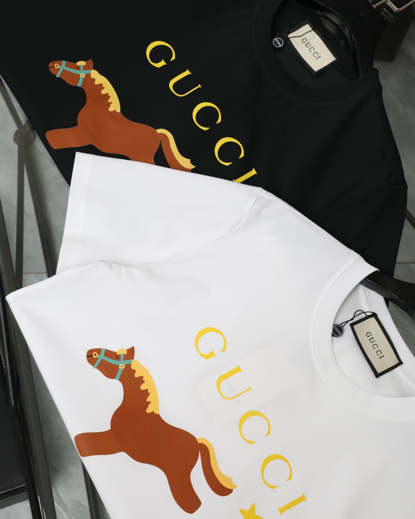GUCCI/古馳  2026新款短袖卡通系列馬年限定小馬印花T恤男女同款

    這款可愛風格的短袖T恤，採用重磅純棉材質，印花是水印透氣性極佳，讓你在炎炎夏日也能保持清爽。
    螺紋領口定制1比1螺紋，二本針雙縫線，不縮水不變形，甄選好棉，成就了軟糯細膩的膚感質感出色，讓你在脫穎而出，還持久耐穿整體是簡約精緻的款式，經過無數次調配的版型上身更顯時筆風度，潮流感拉滿顯瘦“小心機”，落肩設計修飾肩膀厚度，活力滿滿
顏色：  黑色    白色
尺碼：M~2X
尺碼表：圖9