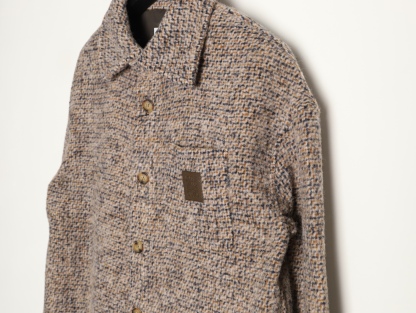 🔝LOEWE羅意威 皮章口袋羊毛混紡外套
採用精心配比的混紡面料，羊毛提供天然保暖與挺括廓形，馬海毛賦予面料細膩蓬松的絨毛感，少量錦綸的餵入則增強耐磨性與抗皺性，三者融合打造中克重的理想厚度，兼顧溫度與輕盈。通過“雙面磨毛”工藝處理，面料表面呈現豐盈的短絨毛肌理，觸感如羊絨般柔軟親膚，同時保留羊毛混紡的筋骨感。微型格紋圖案以沙米色為基底，交織灰、棕、藍三色紗線，通過色織工藝織就，微型格紋尺寸統一，細膩而不張揚，呈現低調的復古韻味。
面料經過3道磨毛工序，確保絨毛長度均勻（约0.3mm）