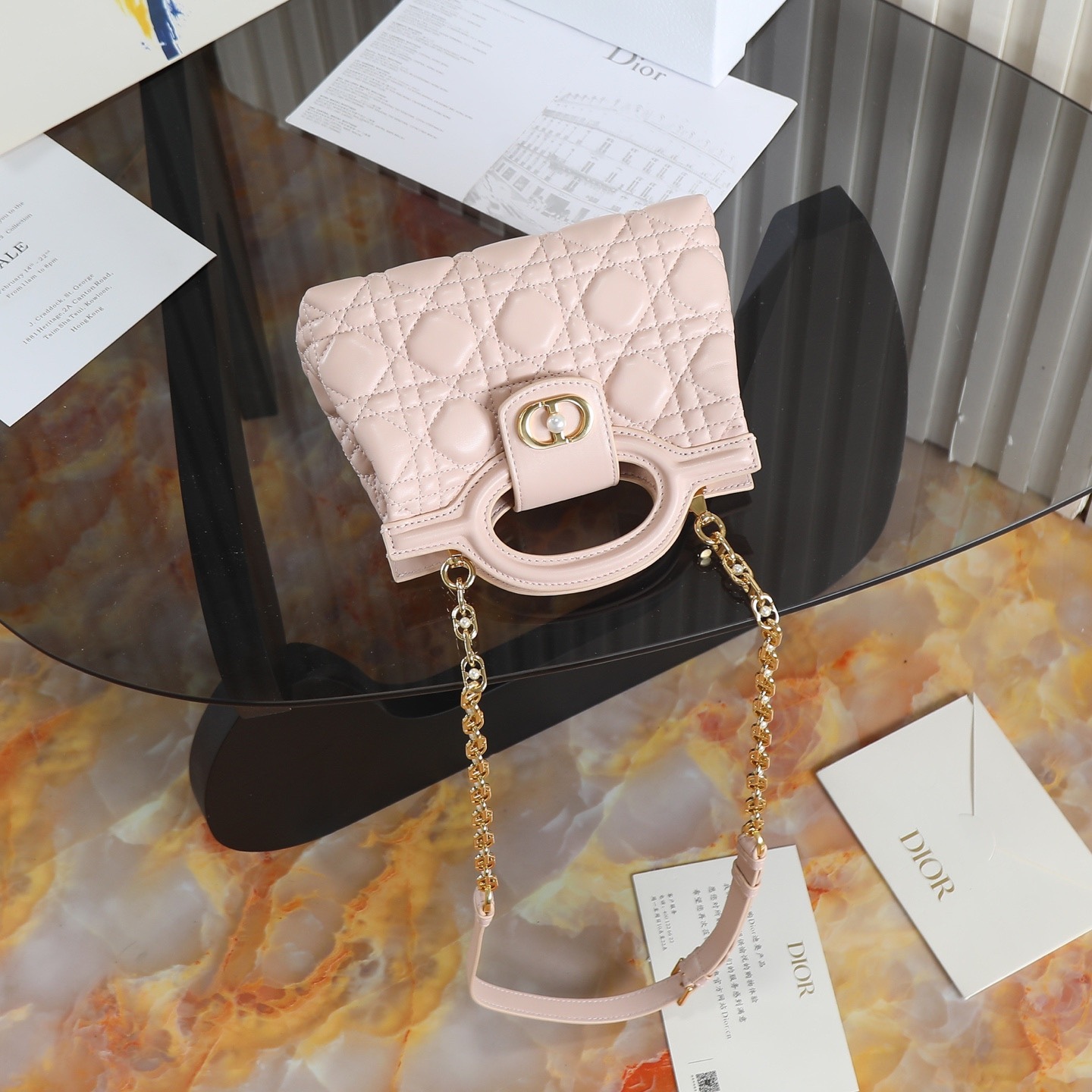 原廠級 粉色鏈條手袋
這款 Dior Jolie Top Handle 迷你鏈條手袋是二零二六早春成衣系列新品，呈現出優雅精緻的設計。採用黑色羊皮革精心製作，飾以藤格紋，翻蓋點綴以金色飾面金屬 CD 標誌和白色樹脂珠飾。內設一個隔層，可收納各種日常用品。搭配雙頂部手柄和可調節、可拆卸 CD 鏈條肩帶，肩帶由皮革帶和 CD 鏈環組成，飾以白色樹脂珠飾，可舒適手提、肩背或斜挎，可與日常或晚裝造型搭配。
