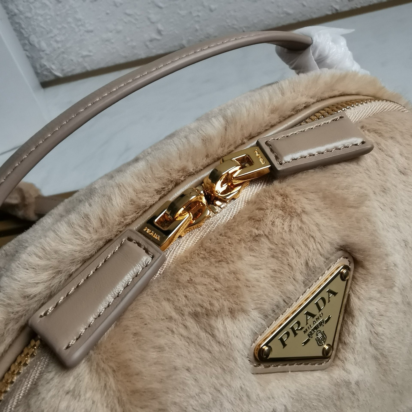 【 原單】🎉最新款迷你手袋🎉1BH208羊毛🎉🎉這款迷你手袋結構挺括，風格百搭，搭配柔軟的羊毛皮，彰顯冬日魅力。皮革細節與雙向拉鍊開合和金屬五金配件錦上添花，飾有塗琺瑯三角形金屬徽標。內配進口小羊皮，上身效果非常酷/時尚，冬天必備爆款🎉寶寶們，趕緊入手吧
尺寸：長19.5x高13x底6cm