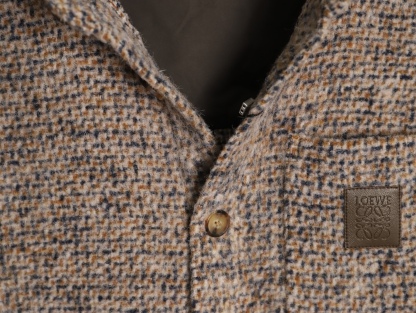 🔝LOEWE羅意威 皮章口袋羊毛混紡外套
採用精心配比的混紡面料，羊毛提供天然保暖與挺括廓形，馬海毛賦予面料細膩蓬松的絨毛感，少量錦綸的餵入則增強耐磨性與抗皺性，三者融合打造中克重的理想厚度，兼顧溫度與輕盈。通過“雙面磨毛”工藝處理，面料表面呈現豐盈的短絨毛肌理，觸感如羊絨般柔軟親膚，同時保留羊毛混紡的筋骨感。微型格紋圖案以沙米色為基底，交織灰、棕、藍三色紗線，通過色織工藝織就，微型格紋尺寸統一，細膩而不張揚，呈現低調的復古韻味。
面料經過3道磨毛工序，確保絨毛長度均勻（约0.3mm）