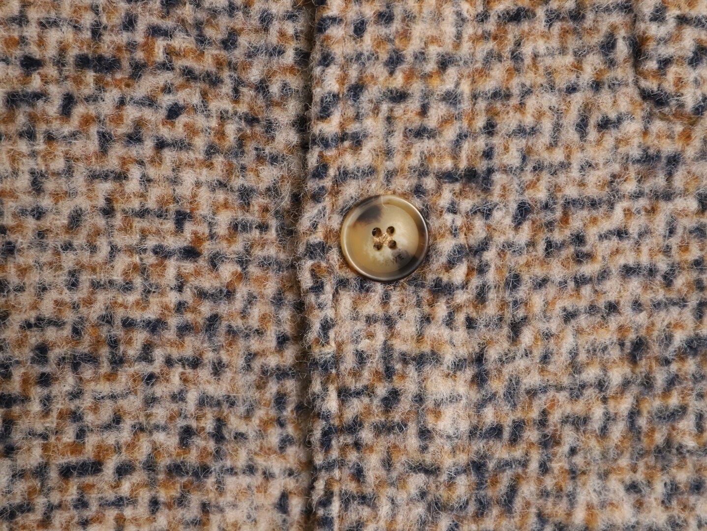 🔝LOEWE羅意威 皮章口袋羊毛混紡外套
採用精心配比的混紡面料，羊毛提供天然保暖與挺括廓形，馬海毛賦予面料細膩蓬松的絨毛感，少量錦綸的餵入則增強耐磨性與抗皺性，三者融合打造中克重的理想厚度，兼顧溫度與輕盈。通過“雙面磨毛”工藝處理，面料表面呈現豐盈的短絨毛肌理，觸感如羊絨般柔軟親膚，同時保留羊毛混紡的筋骨感。微型格紋圖案以沙米色為基底，交織灰、棕、藍三色紗線，通過色織工藝織就，微型格紋尺寸統一，細膩而不張揚，呈現低調的復古韻味。
面料經過3道磨毛工序，確保絨毛長度均勻（约0.3mm）