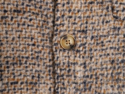 🔝LOEWE羅意威 皮章口袋羊毛混紡外套
採用精心配比的混紡面料，羊毛提供天然保暖與挺括廓形，馬海毛賦予面料細膩蓬松的絨毛感，少量錦綸的餵入則增強耐磨性與抗皺性，三者融合打造中克重的理想厚度，兼顧溫度與輕盈。通過“雙面磨毛”工藝處理，面料表面呈現豐盈的短絨毛肌理，觸感如羊絨般柔軟親膚，同時保留羊毛混紡的筋骨感。微型格紋圖案以沙米色為基底，交織灰、棕、藍三色紗線，通過色織工藝織就，微型格紋尺寸統一，細膩而不張揚，呈現低調的復古韻味。
面料經過3道磨毛工序，確保絨毛長度均勻（约0.3mm）