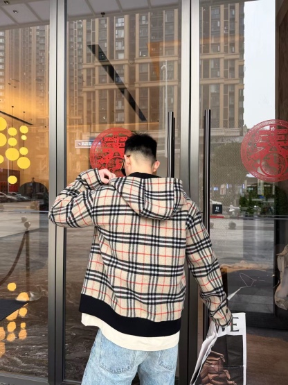 🔝BURBERRY巴寶莉BBR 雙面穿羊毛連帽外套
精選雙面羊毛斜紋面料，通過獨特的拉絨工藝處理，使表層呈現細膩豐盈的絨毛質感，觸感如雲朵般柔軟親膚，同時保留羊毛天然的保暖性與透氣性。一面以沈穩黑色演繹低調奢華，另一面則鋪滿標誌性的紅、黑、駝三色交織的經典圖案，既是品牌視覺符號，也為穿搭注入復古氣息。雙面可穿的設計，讓一件外套擁有兩種風格。
選用優質羊絨纖維進行精細紡紗，確保紗線的均勻性和強度。然後，通過先進的織造技術將紗線織成具有雙面效果的毛呢面料。
面料在裁剪前會經過預縮處理