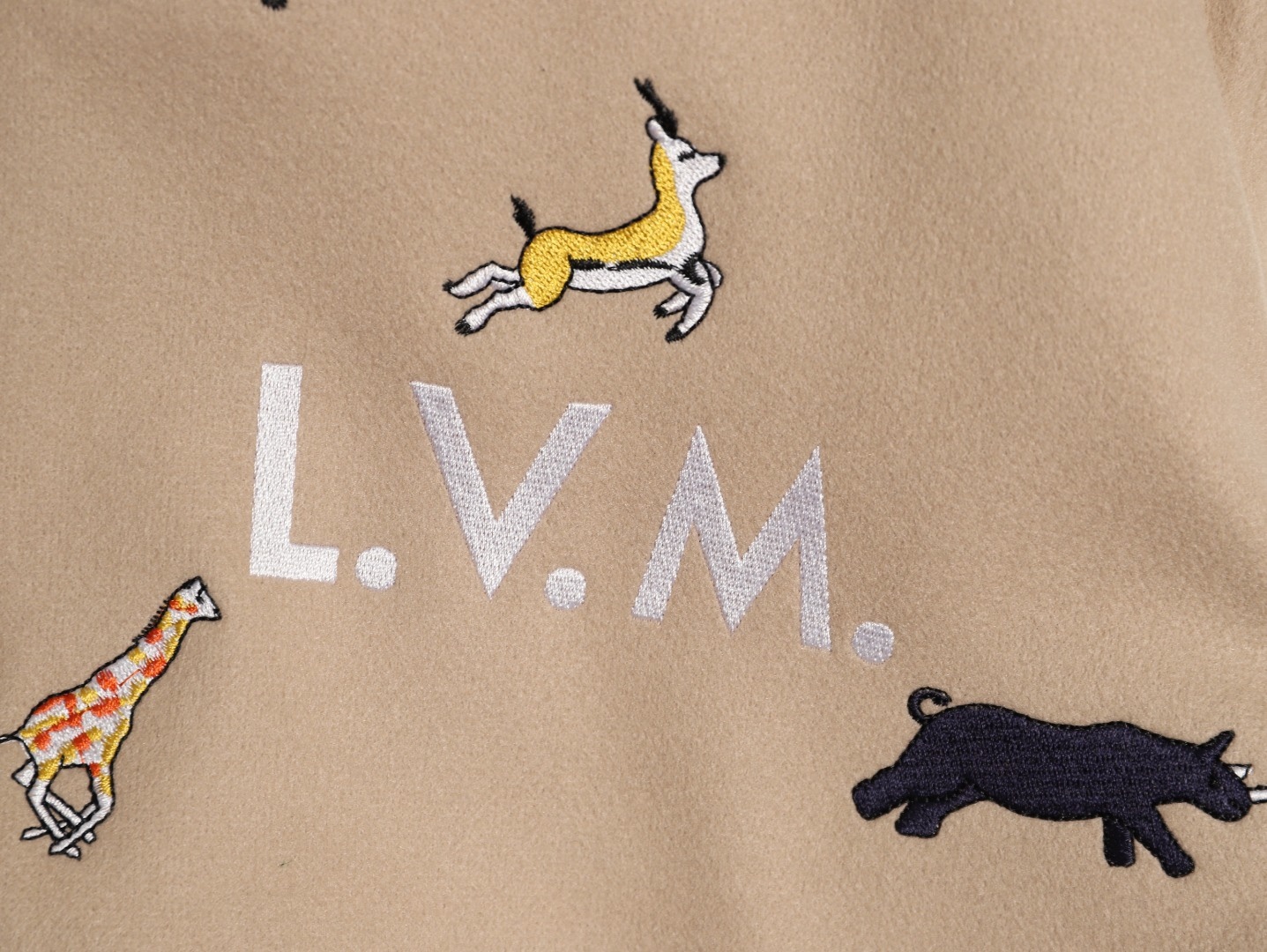 Louis Vuitton/路易威登 26ss 動物樂園刺繡棒球服外套
材質拼接：衣身採用淺卡其色羊毛混紡面料，柔軟且有挺括感；袖子為奶白色荔枝紋牛皮，質感細膩，淺色系搭配更顯清爽。

• 裝飾亮點：衣身滿印精緻動物刺繡（長頸鹿、斑馬、大象、黑豹等）與棕櫚樹圖案，左胸綴有“L.V.M.”字母標識，充滿童趣與度假感，辨識度極高。

• 版型結構：經典棒球服版型，羅紋條紋領口/袖口/下擺，防風收型；正面按扣開合，兩側配白色撞色插袋，兼顧實用性與設計感。
N SIZE:S-XL
