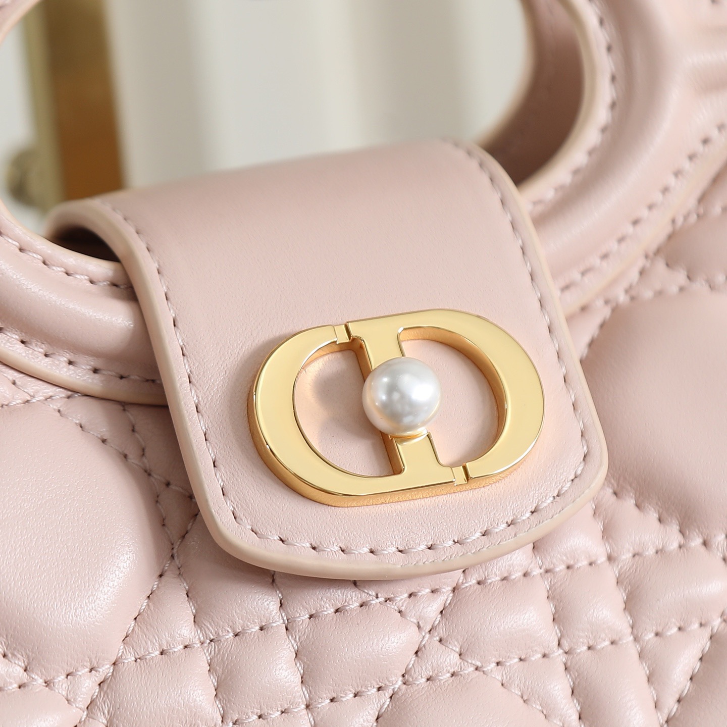 原廠級 粉色鏈條手袋
這款 Dior Jolie Top Handle 迷你鏈條手袋是二零二六早春成衣系列新品，呈現出優雅精緻的設計。採用黑色羊皮革精心製作，飾以藤格紋，翻蓋點綴以金色飾面金屬 CD 標誌和白色樹脂珠飾。內設一個隔層，可收納各種日常用品。搭配雙頂部手柄和可調節、可拆卸 CD 鏈條肩帶，肩帶由皮革帶和 CD 鏈環組成，飾以白色樹脂珠飾，可舒適手提、肩背或斜挎，可與日常或晚裝造型搭配。
